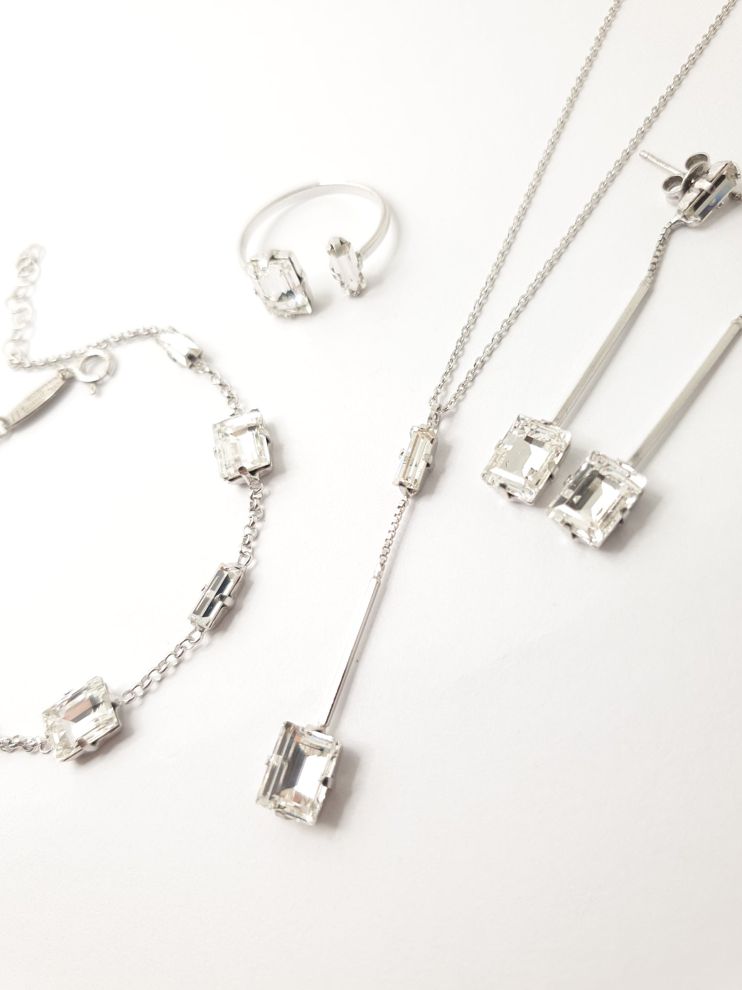 Swarovski Set aus italienischem Silber bestehend aus Armband mit weißen viereckigen Kristallen verziert, Kette mit langem Anhänger mit zwei Kristallen und Hängeohrringe.